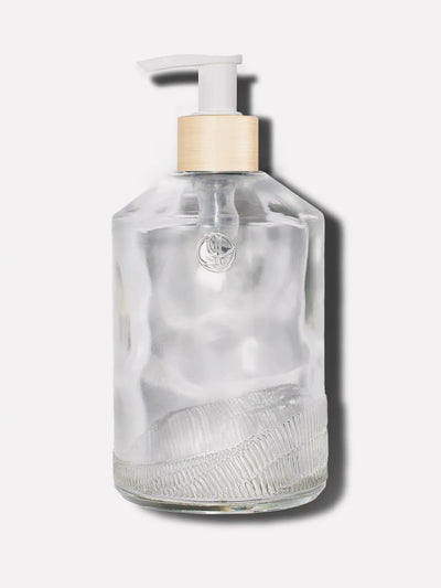 Clear glass custom bottle with brush gold neck on a white pump.
