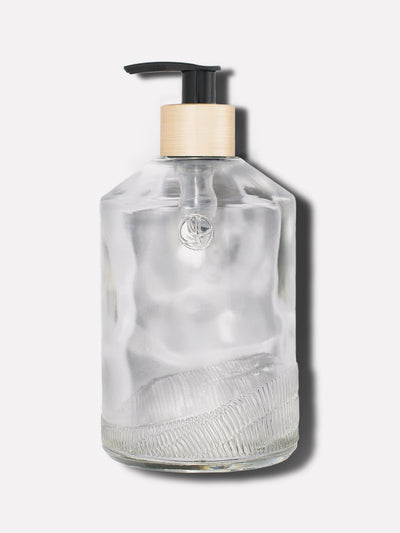 Clear glass custom bottle with brush gold neck on a black pump.