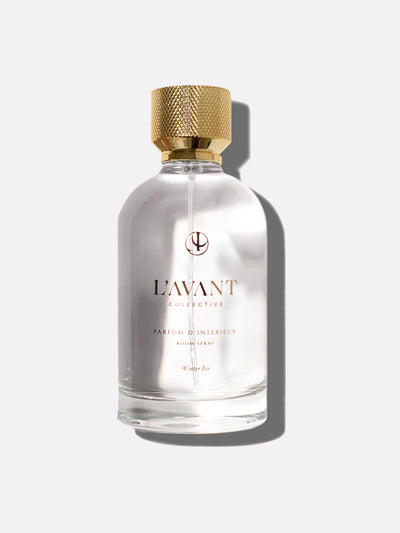 Clear glass bottle of Winter Fir Room Fragrance. Gold top with gold writing on bottle.