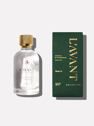 Clear glass bottle of Winter Fir holiday Room Fragrance. Gold top with gold writing on bottle. Green retail box on right side of image with Gold Foil lettering on the box.
