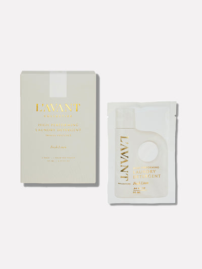 Travel Pouch Set in the Fresh Linen scent. The packaging features an elegant, minimalist design with soft cream tones and gold foil lettering. The box on the left showcases the product name and details, while the travel-friendly detergent pouch on the right is compact and convenient, designed for single-use washing. The luxurious aesthetic reflects the brand's commitment to high-quality, eco-friendly, and stylish home care essential