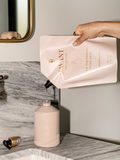 Woman pouring citrus bergamot scented hand soap into a blush pink pump dispenser bottle